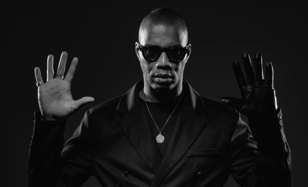 Black and white portrait of ROWZ JR with both hands raised